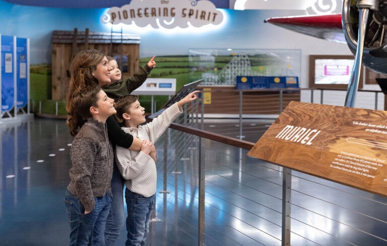 Mother with three children standing in front of plane in museum