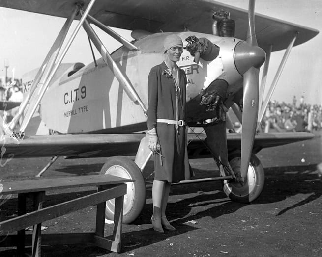 Amelia Earhart standing in front of plane in 1928