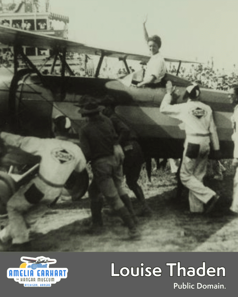 Louise Thaden sitting atop an open cockpit plane